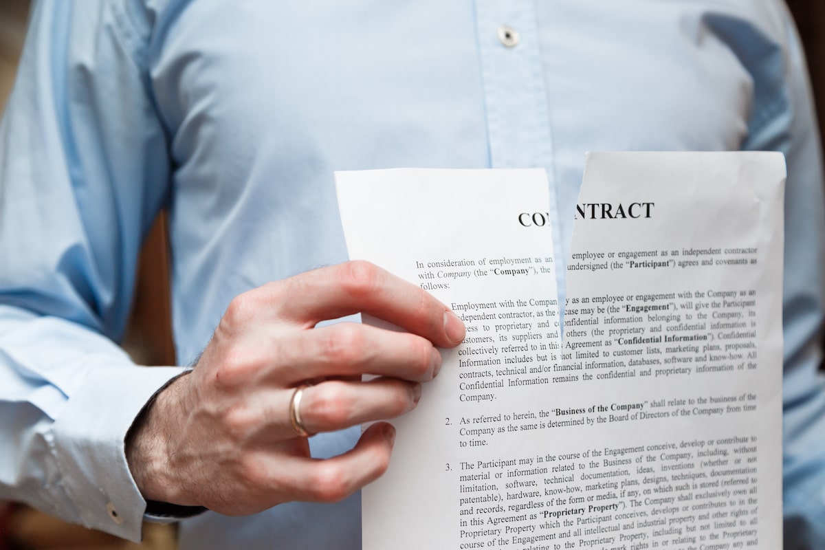Man tears up a contract, signifying a breach of contract