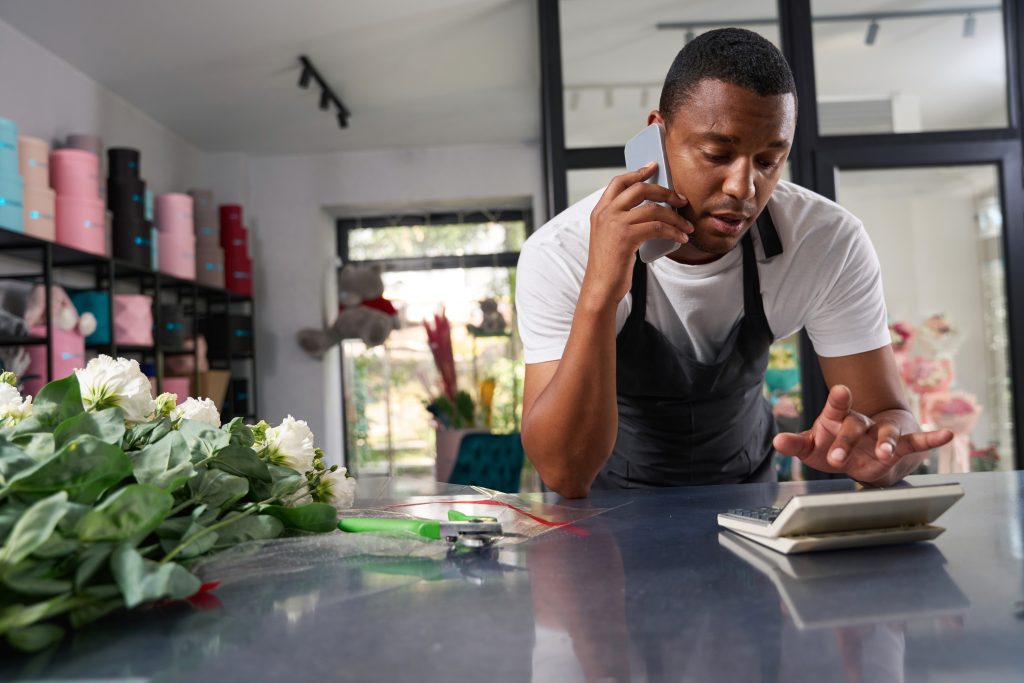 Florist calculating prices on phone at counter
