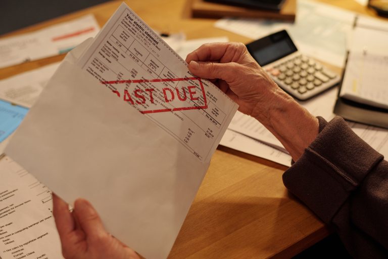 Hands holding past due bill with calculator