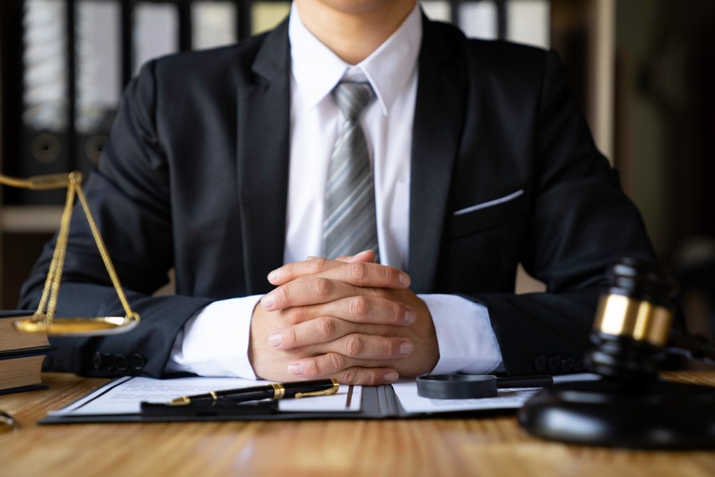 Lawyer hands clasped at desk with legal items